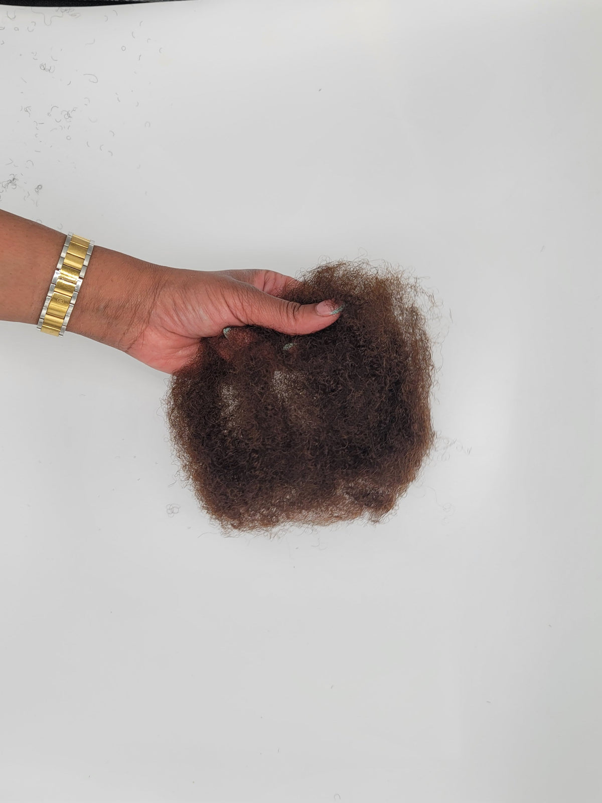 Person separating a bundle of DKEight bundle of loose bulk 4C brown hair against a white background