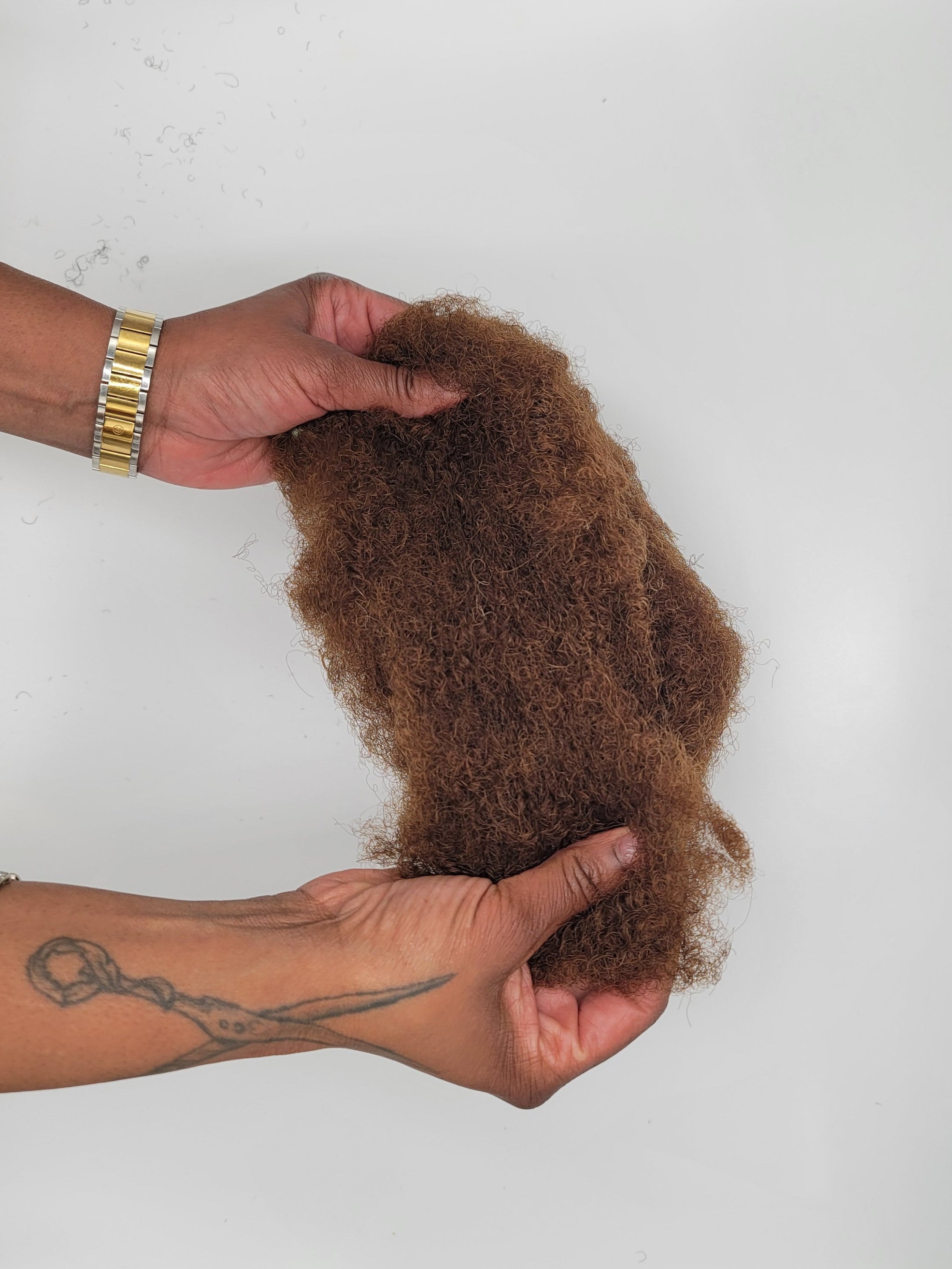 Person holding DKEight bundle of loose bulk 4C brown hair against a white background