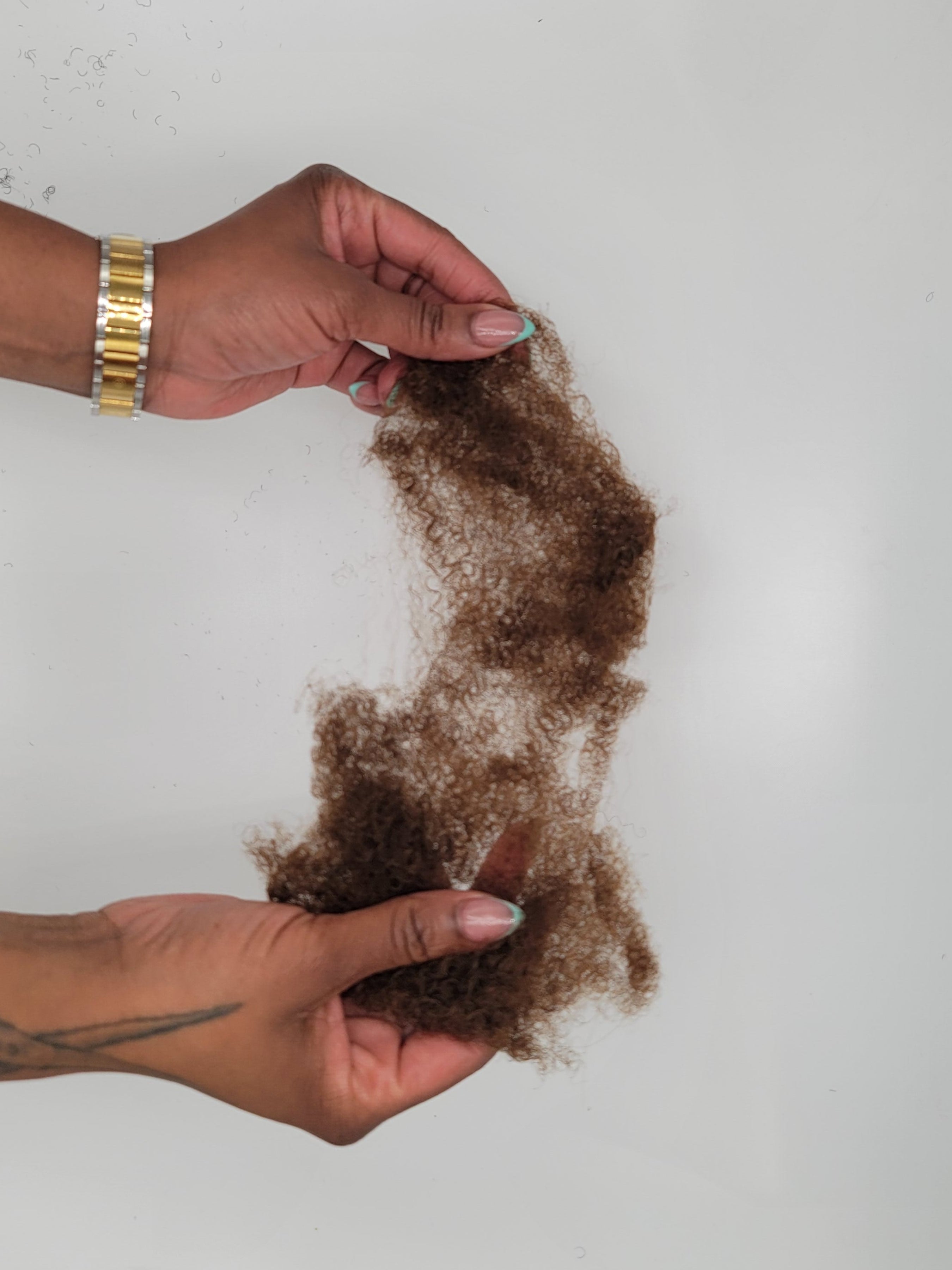 Person seperating a bundle of DKEight bundle of loose bulk 4C brown hair against a white background